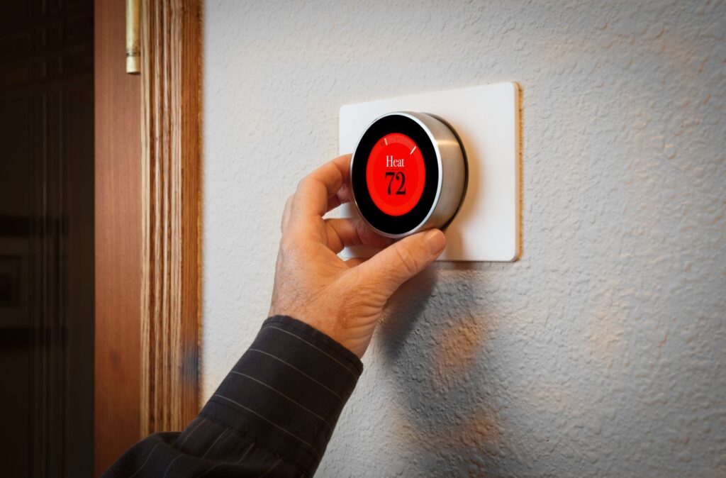 Common Heating System Thermostat Problems in Piqua Homes 8 Hand adjusting a modern thermostat displaying "Heat 72," relevant to HVAC system troubleshooting in Piqua homes.
